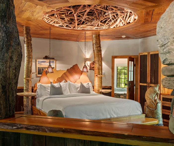 Rustic bedroom with a unique wooden bed frame and a ceiling made of intertwined branches at Winvian Farm.