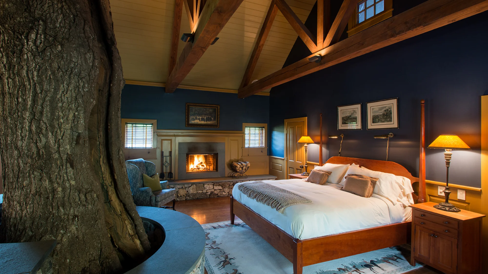 Interior of the Charter Oak Cottage at Winvian Farm with a tree trunk, fireplace, and vaulted ceiling.