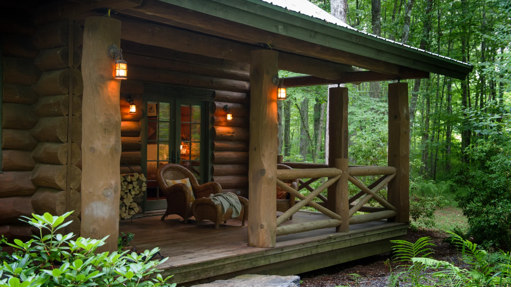 Cozy porch of the Log Cabin Cottage at Winvian Farm with wicker chairs and warm lighting.